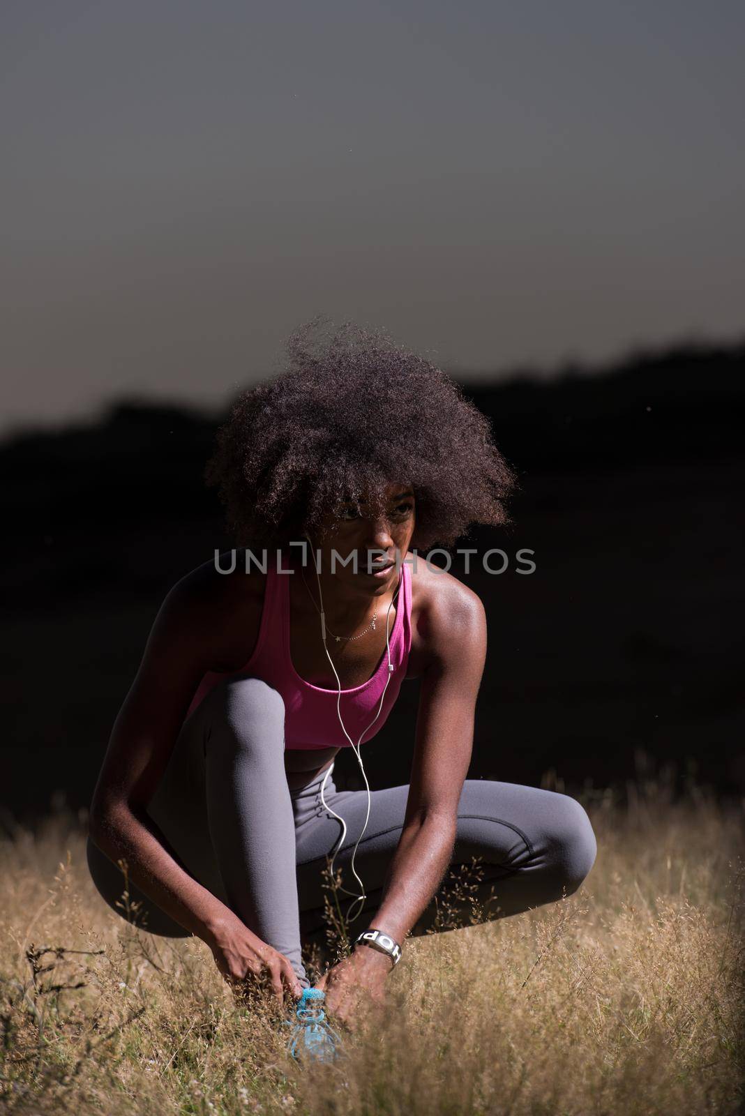 young African american woman runner tightening shoe lace in nature  Fitness, people and healthy lifestyle