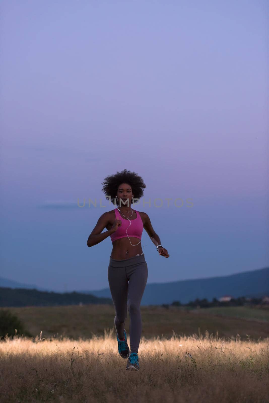 young African american woman runner with headphones jogging outdoors in nature beautiful summer night - Fitness, people and healthy lifestyle