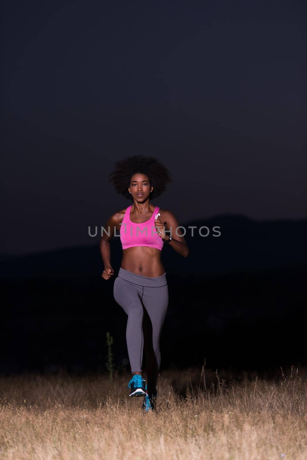 young African american woman runner with headphones jogging outdoors in nature beautiful summer night - Fitness, people and healthy lifestyle