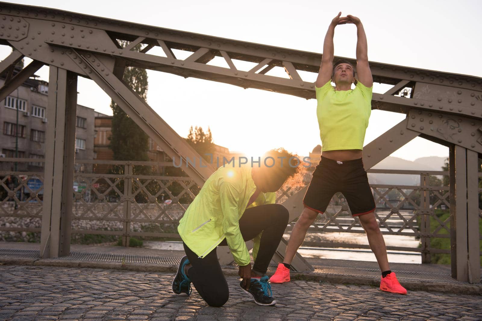 Young multiethnic jogging couple warming up and stretching before morning running in the city