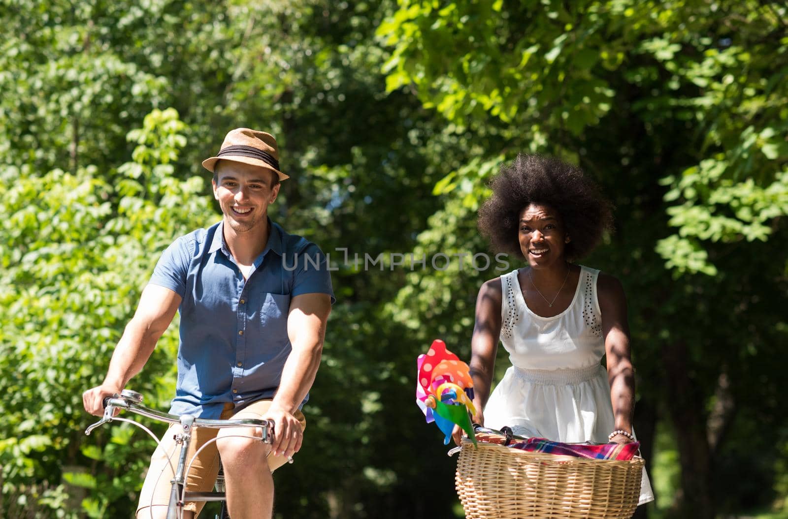 a young man and a beautiful African American girl enjoying a bike ride in nature on a sunny summer day