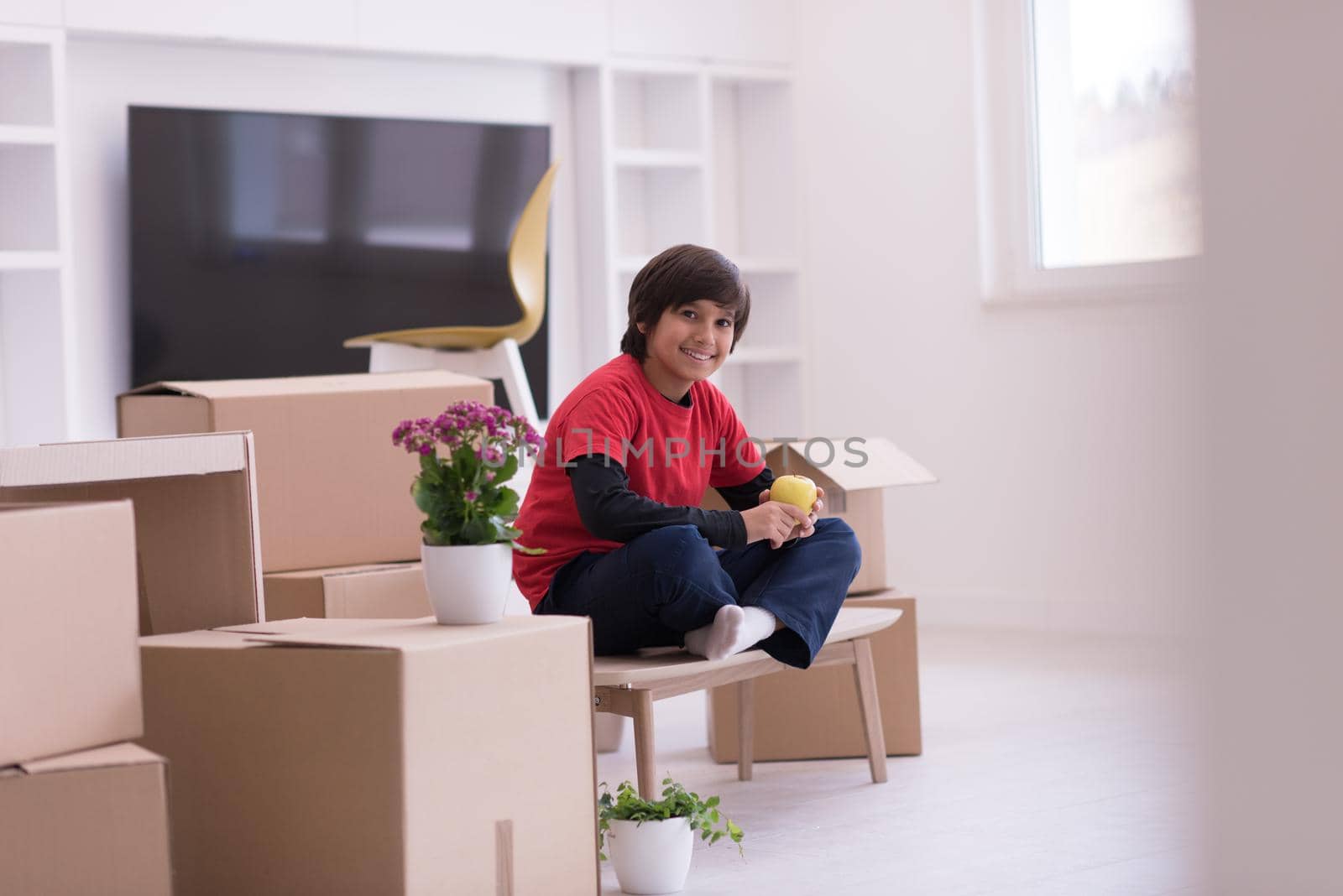boy sitting on the table with cardboard boxes around him by dotshock