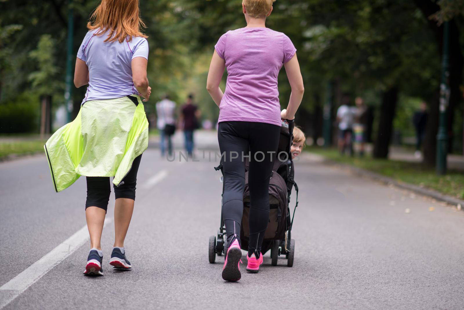 women with baby stroller jogging together by dotshock