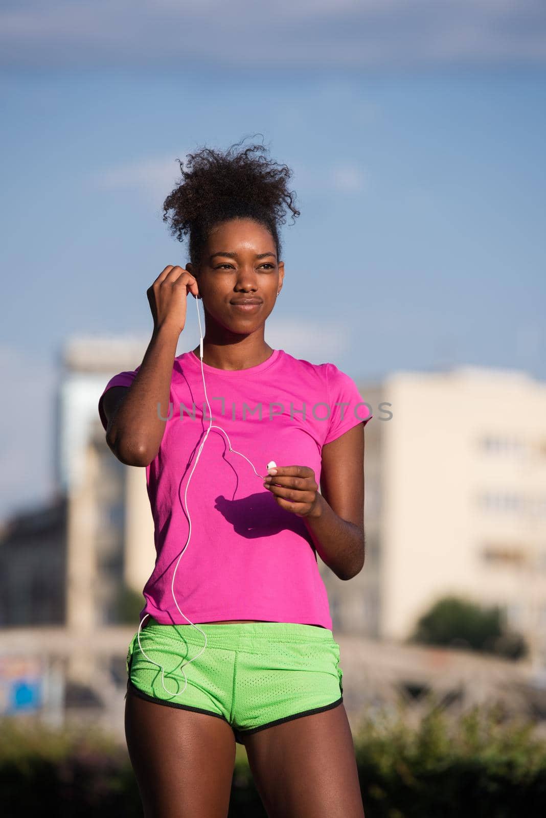 portrait of a young African American girl with headphones to run beautiful summer morning on city streets