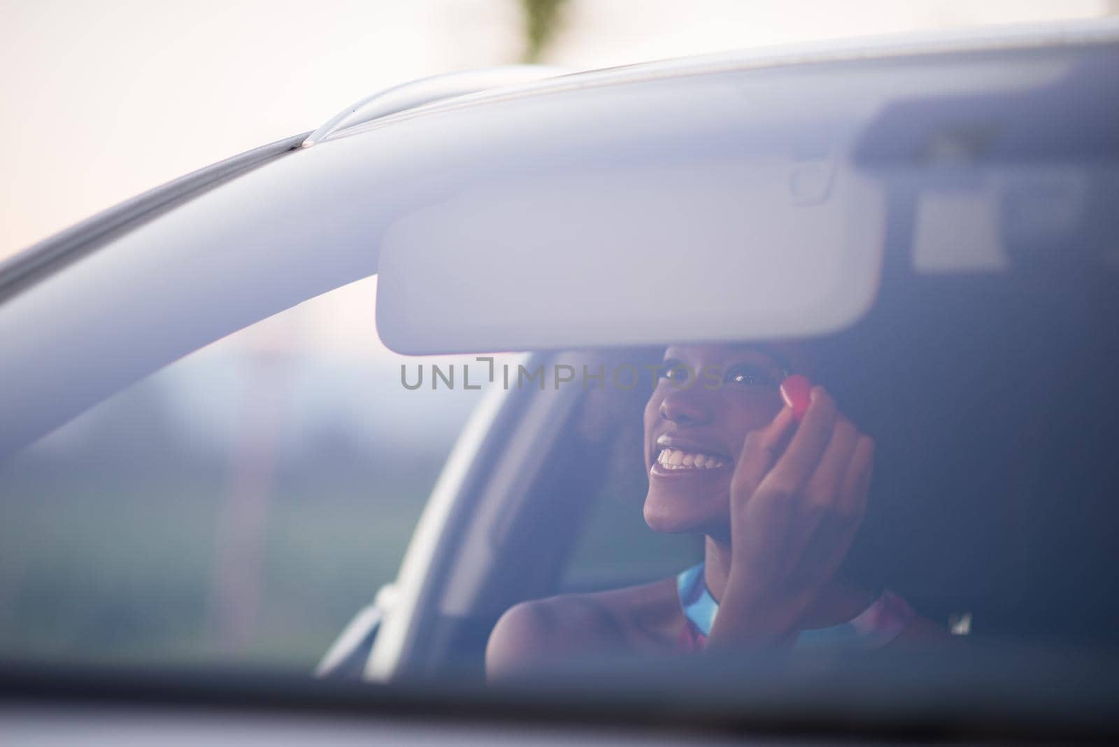 young beautiful African American woman making makeup while driving car