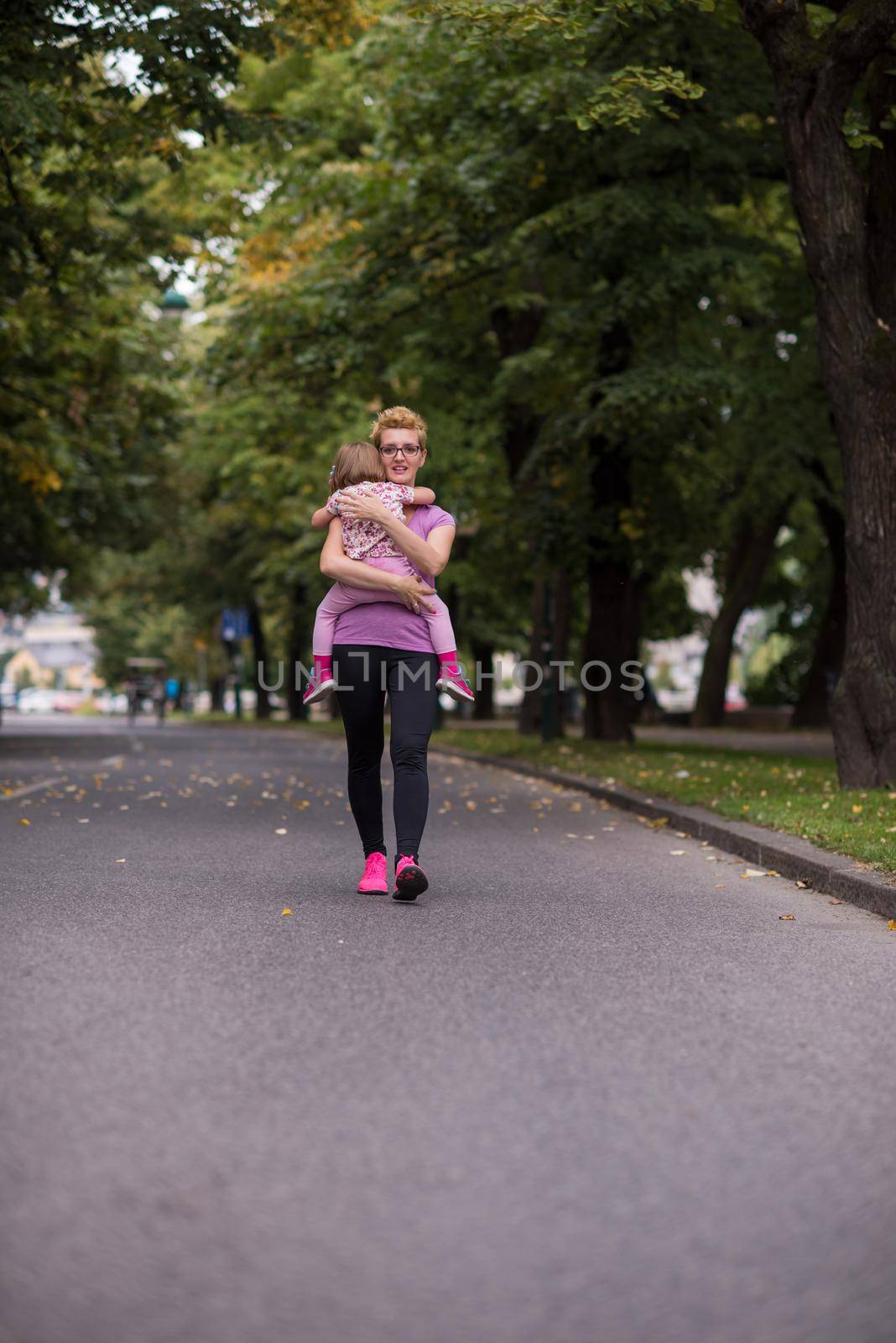 jogging mother carries little daughter by dotshock