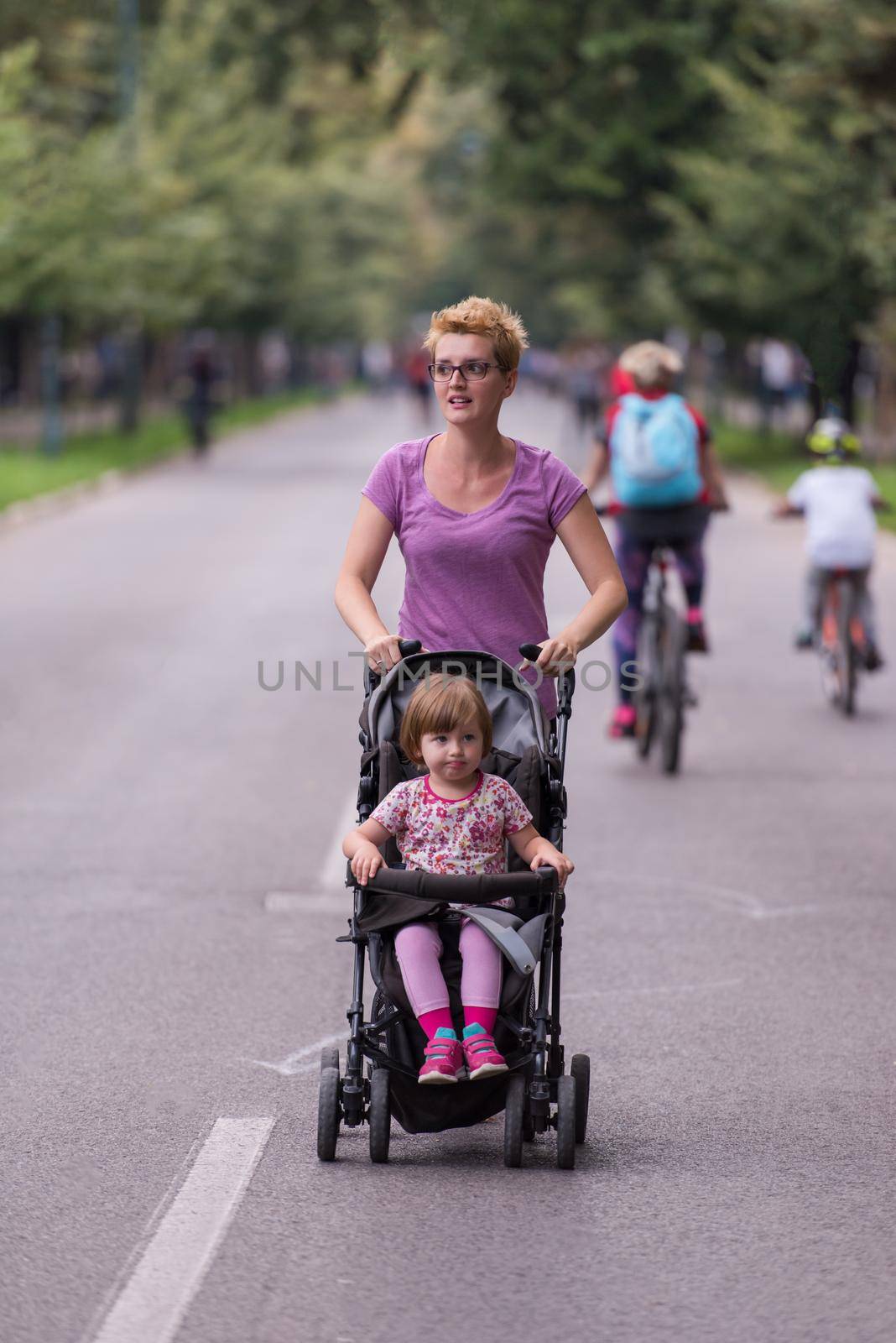 young healthy mother jogging while pushing a baby stroller at city park