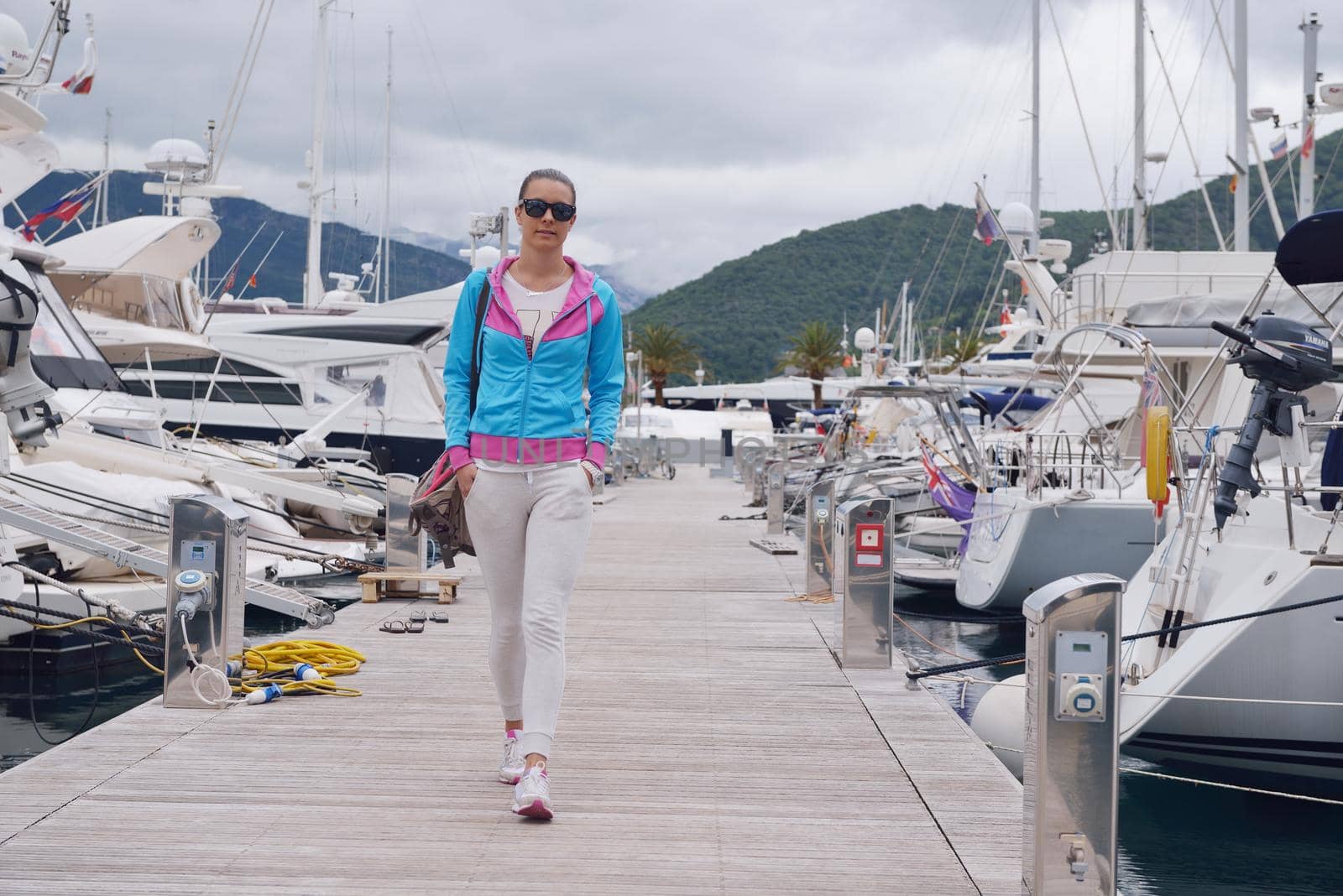 relaxed young woman walking in marina with yacht boats in bacground