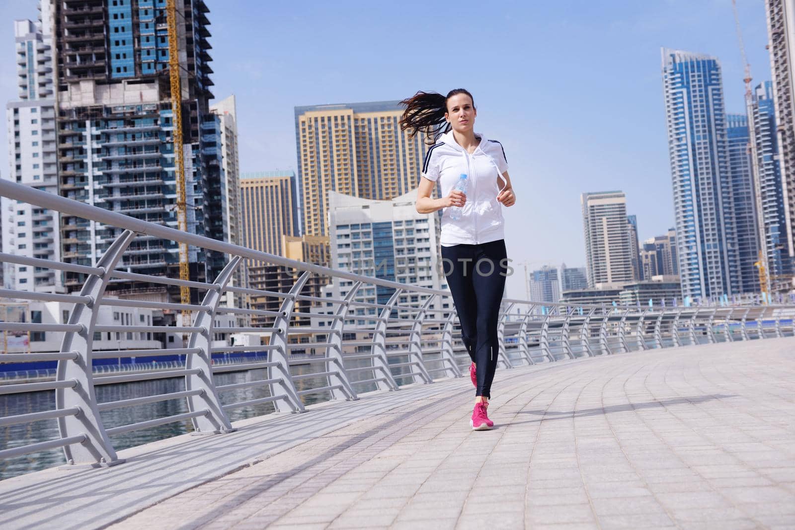 Running in city park. Woman runner outside jogging at morning with Dubai urban scene in background