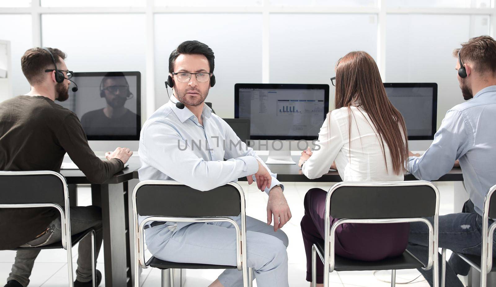 rear view.business man with a headset and his colleagues sitting in the office . photo with copy space