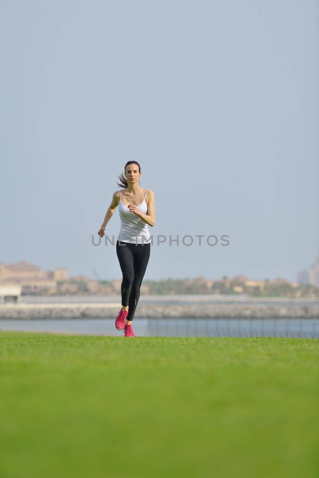 Running in city park. Woman runner outside jogging at morning with Dubai urban scene in background