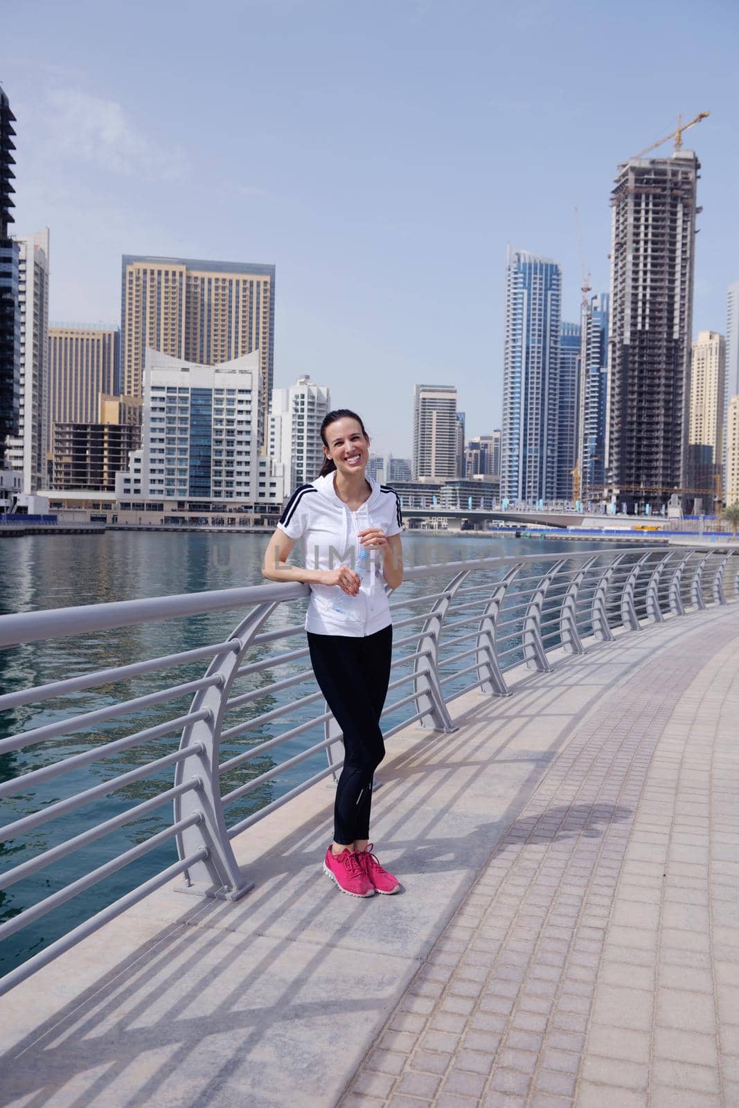 Running in city park. Woman runner outside jogging at morning with Dubai urban scene in background