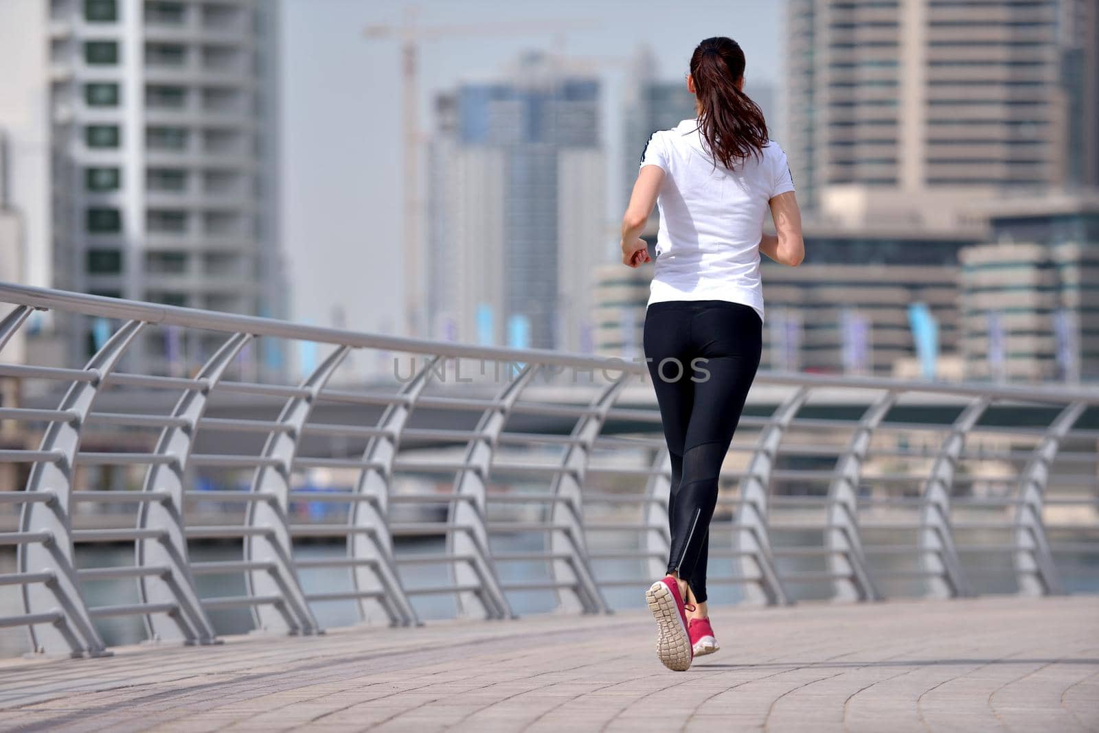 Running in city park. Woman runner outside jogging at morning with Dubai urban scene in background