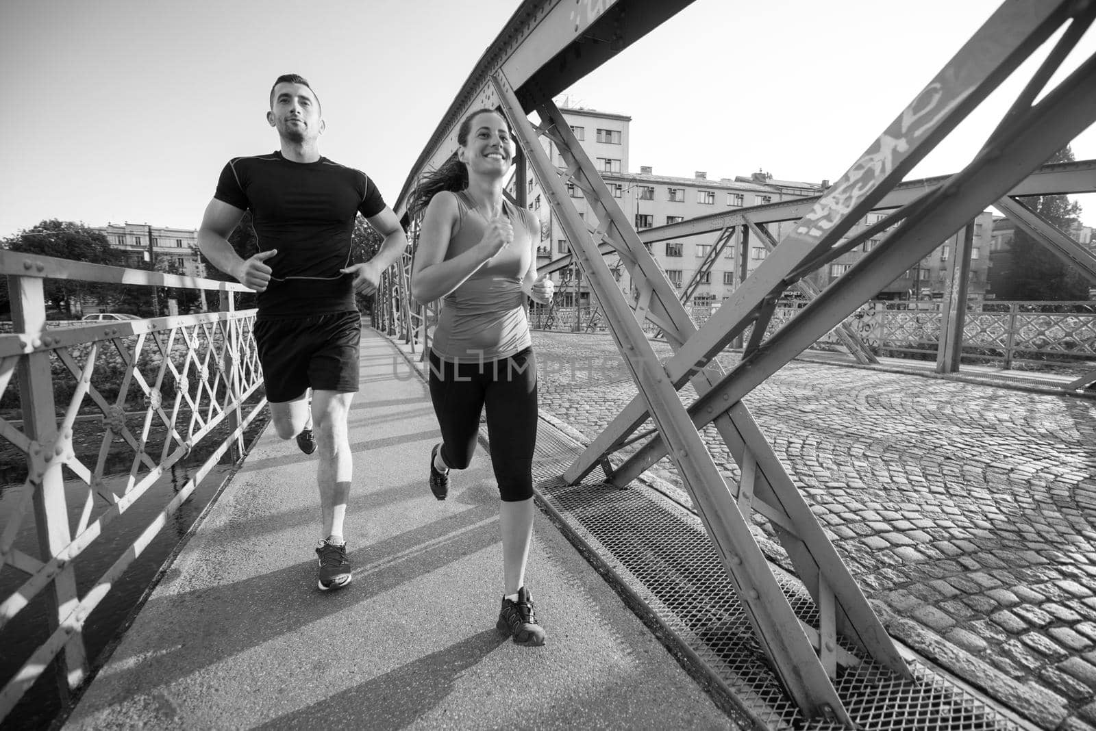 young couple jogging across the bridge in the city by dotshock