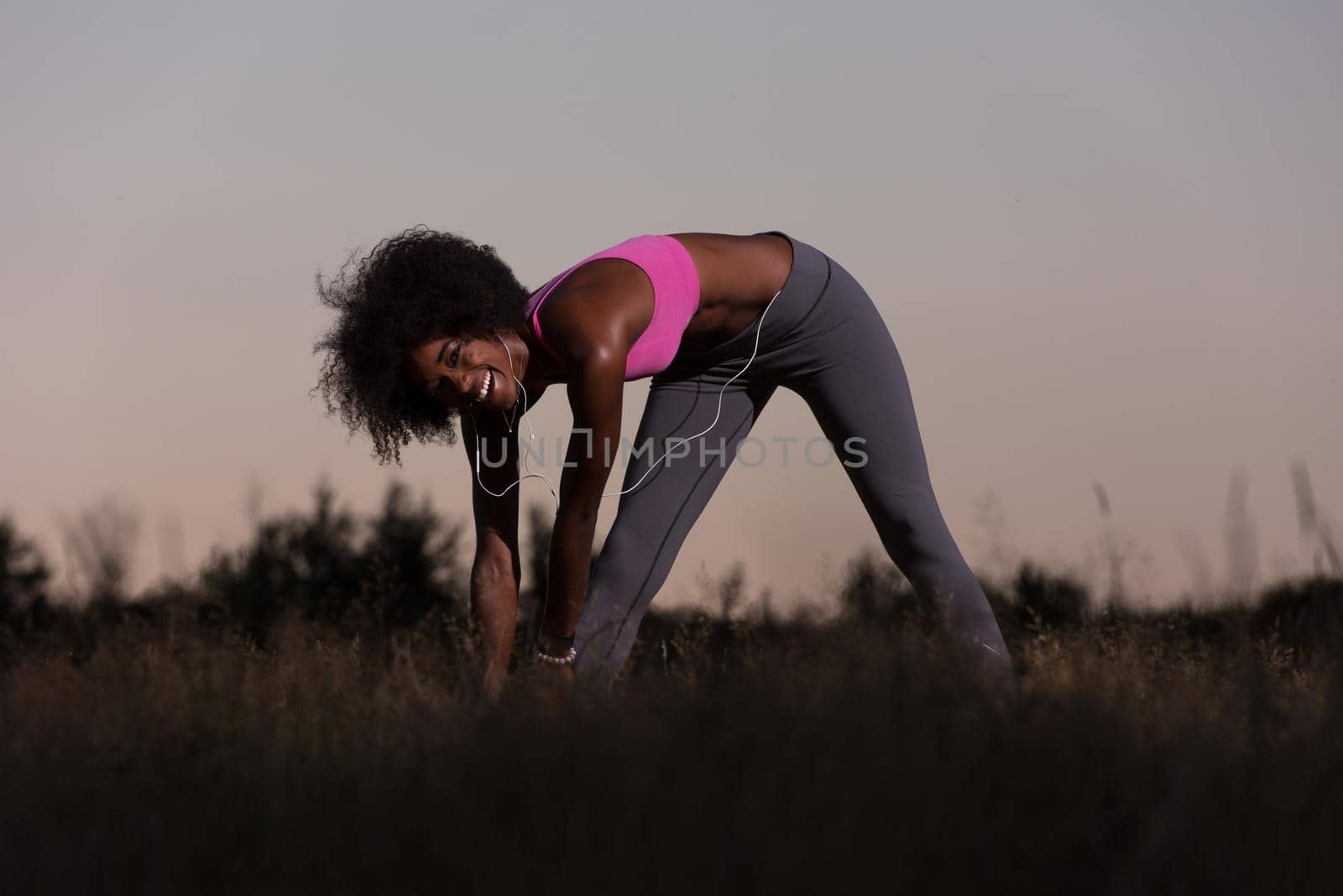 Young healthy black woman is doing stretching exercise relaxing and warm up after jogging and running in the nature beautiful summer evening