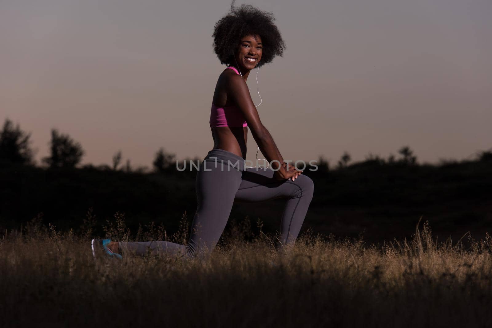 Young healthy black woman is doing stretching exercise relaxing and warm up after jogging and running in the nature beautiful summer evening