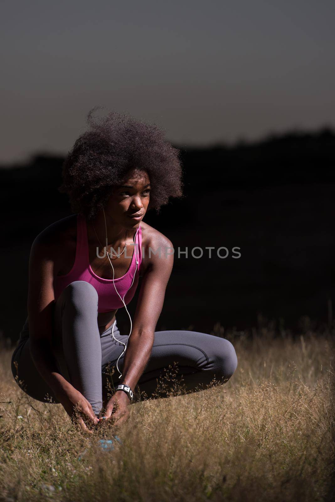 young African american woman runner tightening shoe lace in nature  Fitness, people and healthy lifestyle