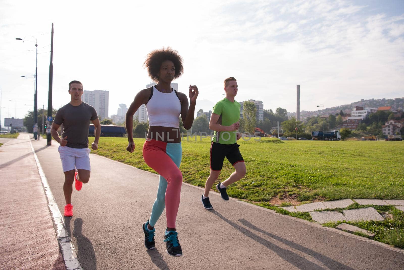 multiethnic group of young people on the jogging beautiful morning as the sun rises in the streets of the city