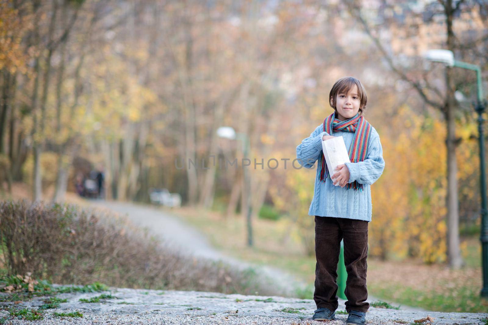 cute little boy in park eating popcorn in autumn cloudy day