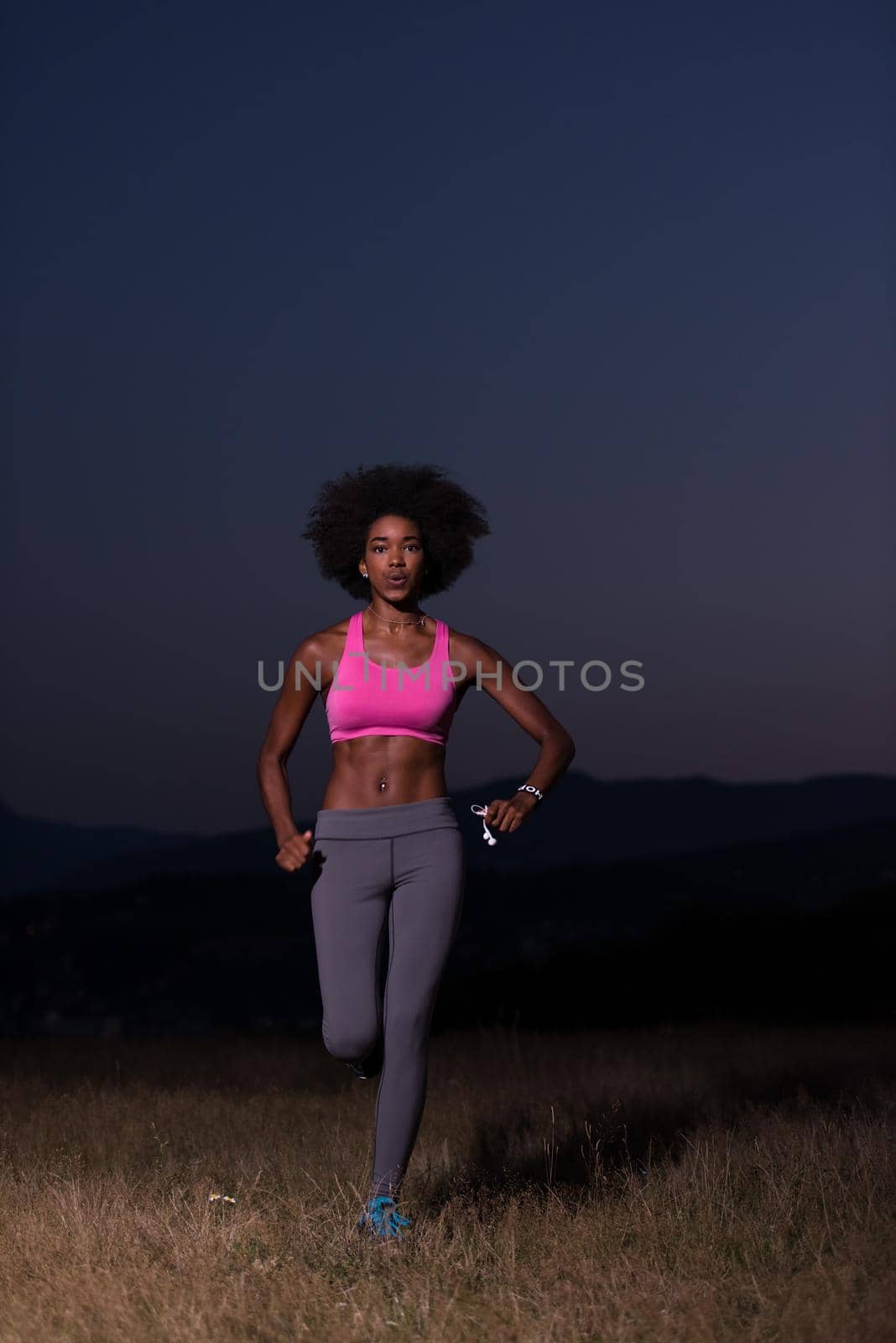 young African american woman runner with headphones jogging outdoors in nature beautiful summer night - Fitness, people and healthy lifestyle