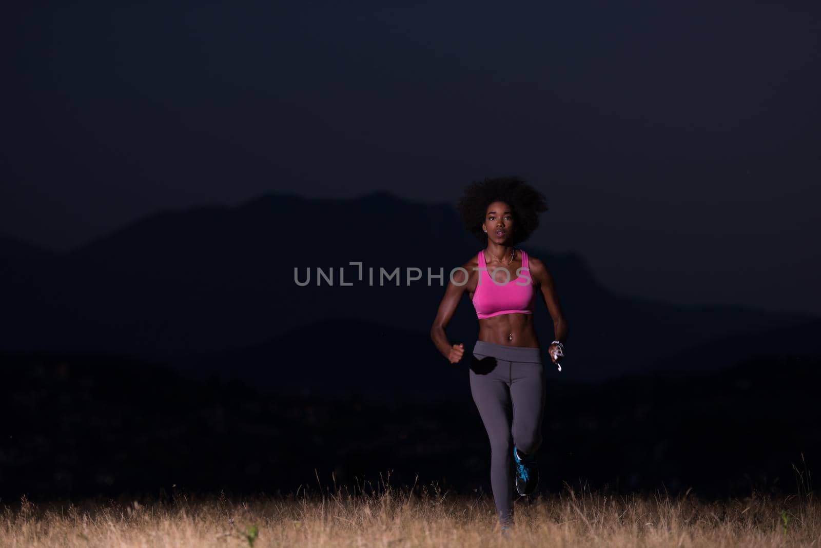 young African american woman runner with headphones jogging outdoors in nature beautiful summer night - Fitness, people and healthy lifestyle