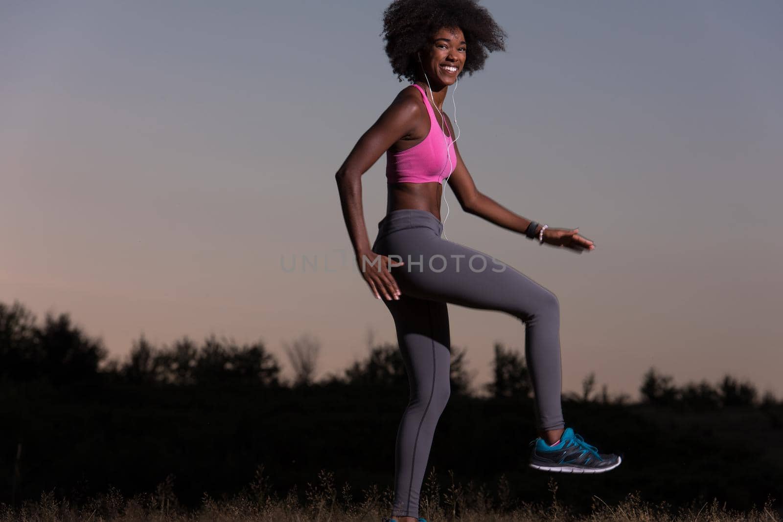 Young healthy black woman is doing stretching exercise relaxing and warm up after jogging and running in the nature beautiful summer evening