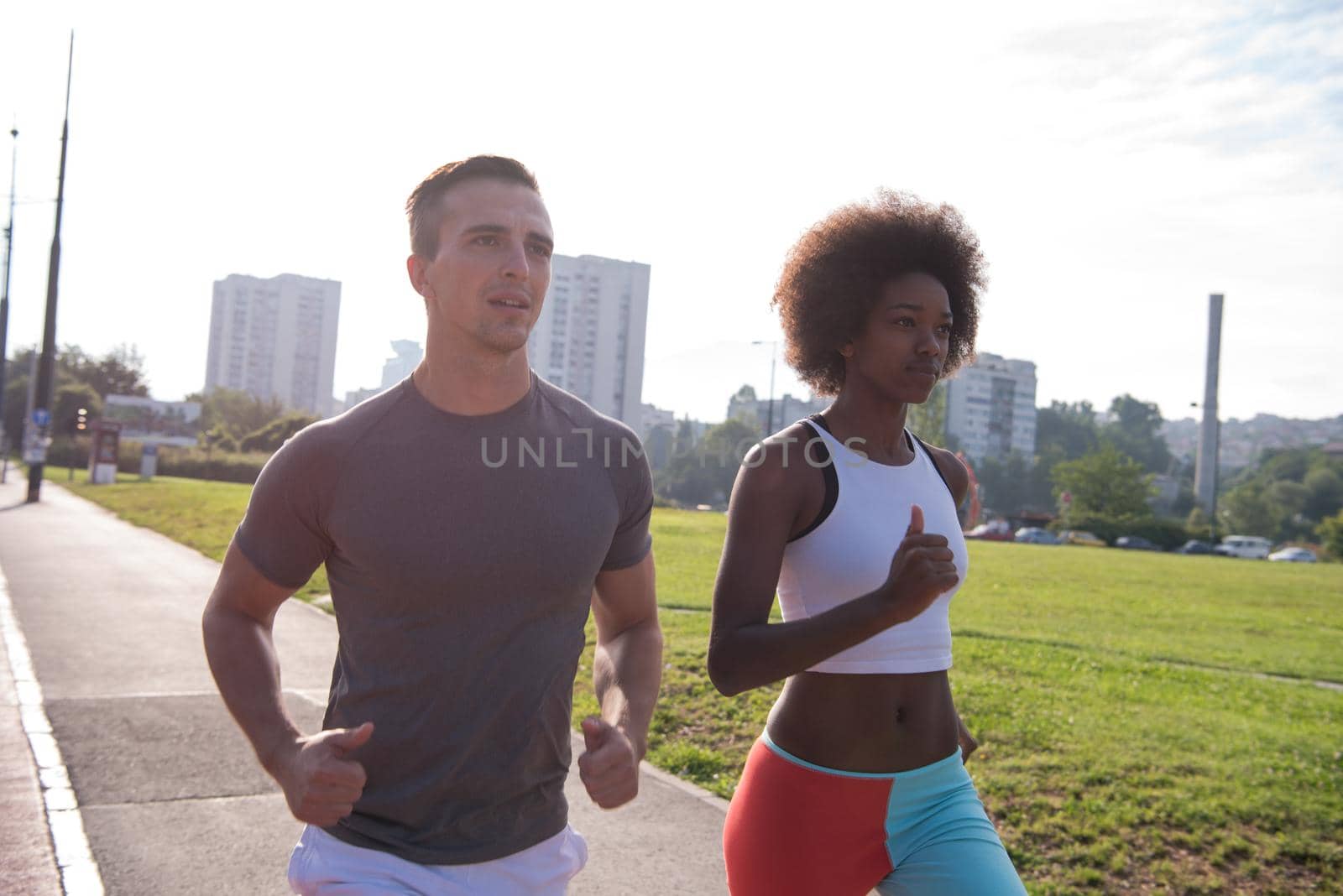 multiethnic group of young people on the jogging beautiful morning as the sun rises in the streets of the city