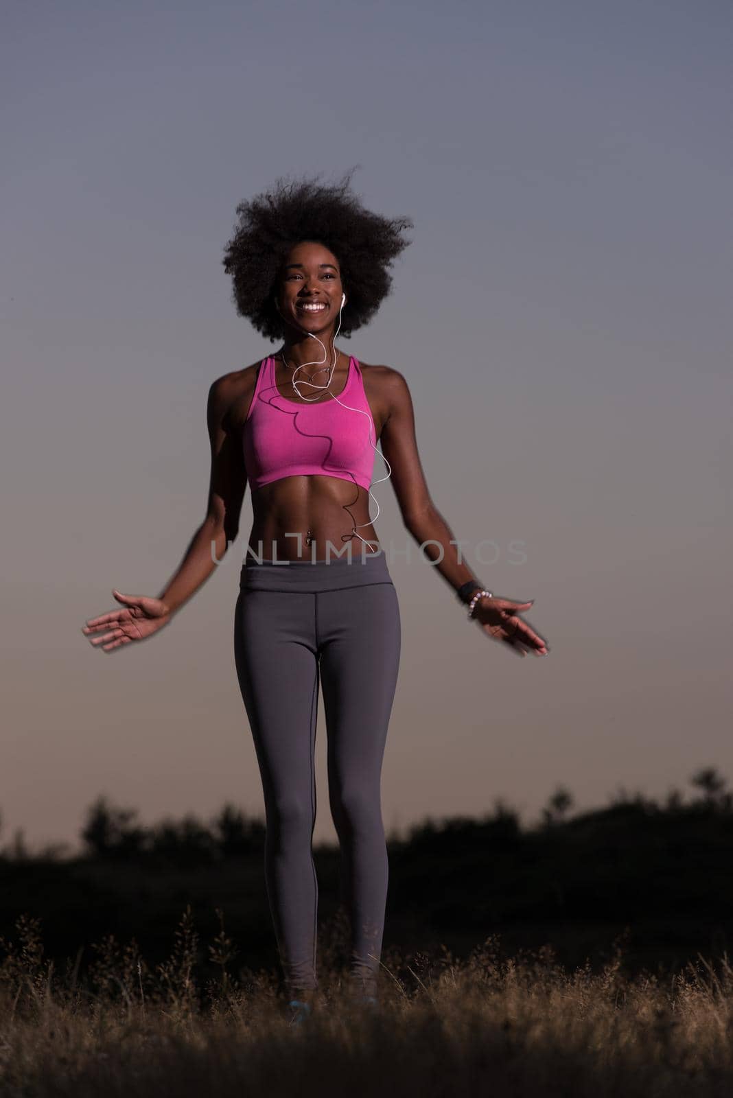 Young healthy black woman is doing stretching exercise relaxing and warm up after jogging and running in the nature beautiful summer evening