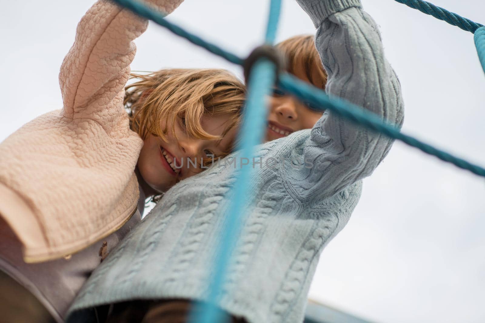 cutte little girl and boy in childrens park having fun and joy while playing in playground on autumn cloudy day