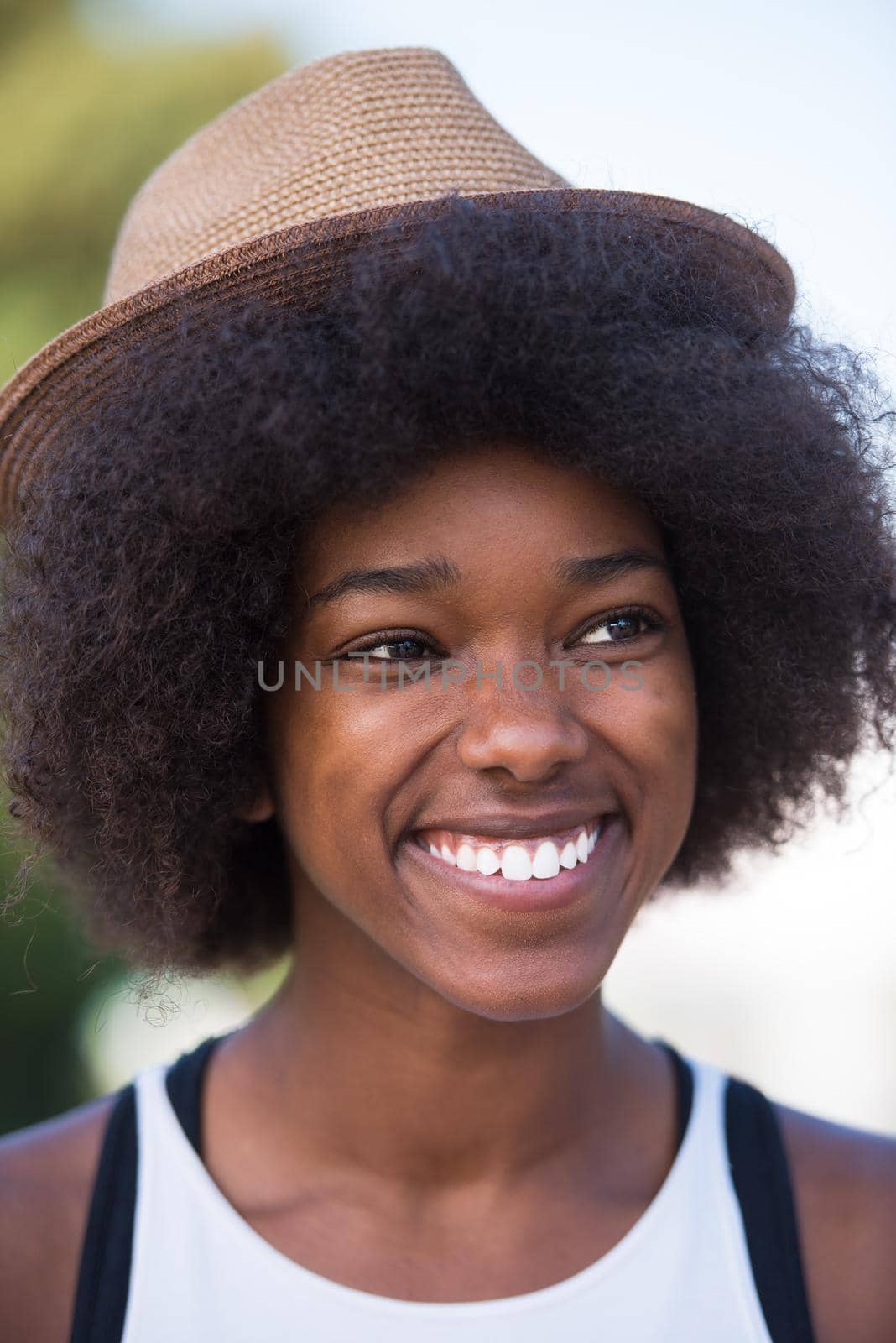 Close up portrait of a beautiful young african american woman smiling and looking up on a beautiful sunny day