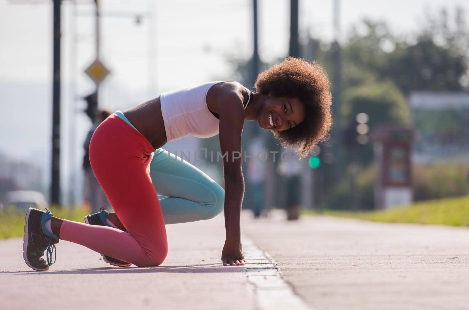 portrait of a young beautiful African American girl doing stretching beautiful summer morning on the streets of the city
