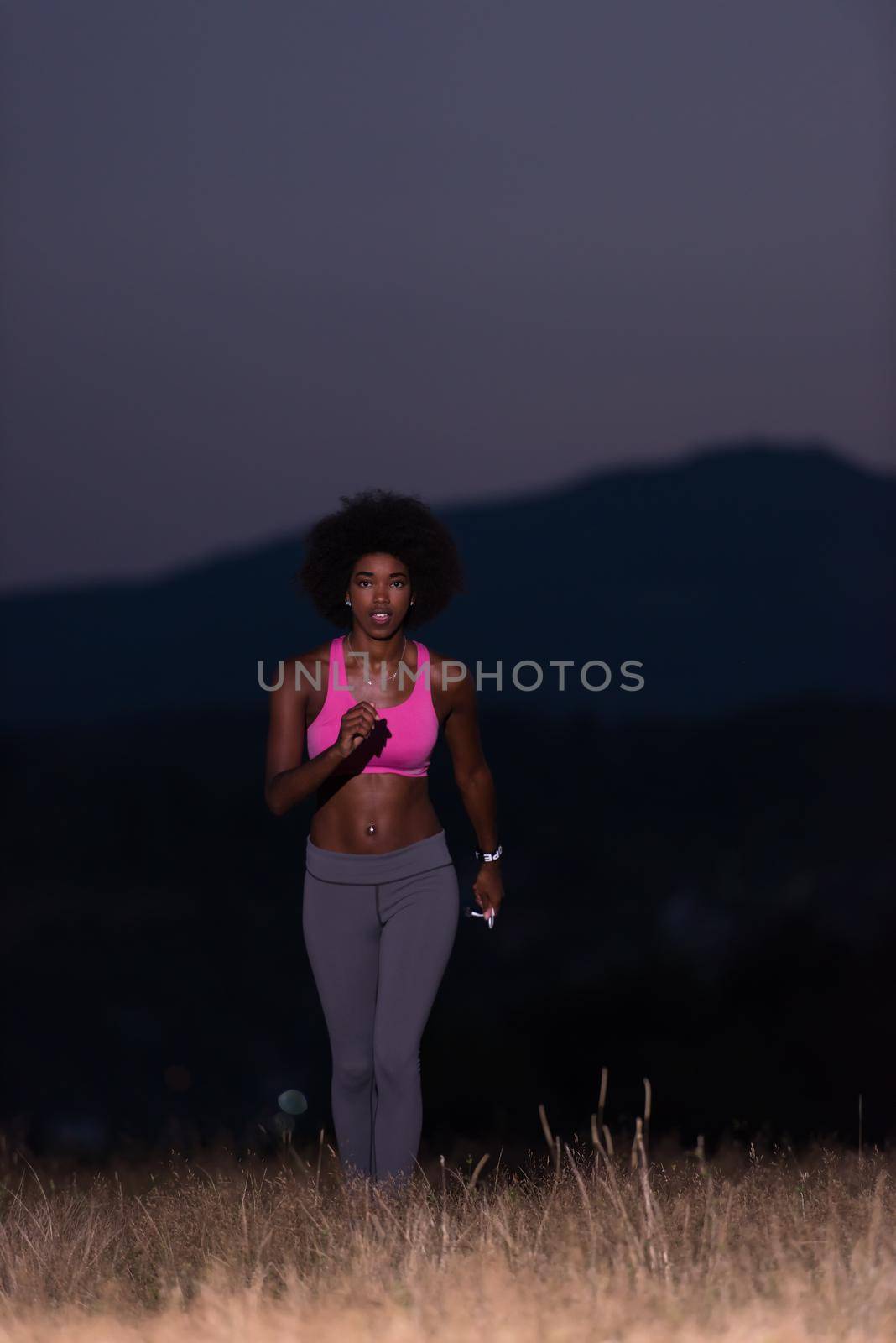 young African american woman runner with headphones jogging outdoors in nature beautiful summer night - Fitness, people and healthy lifestyle