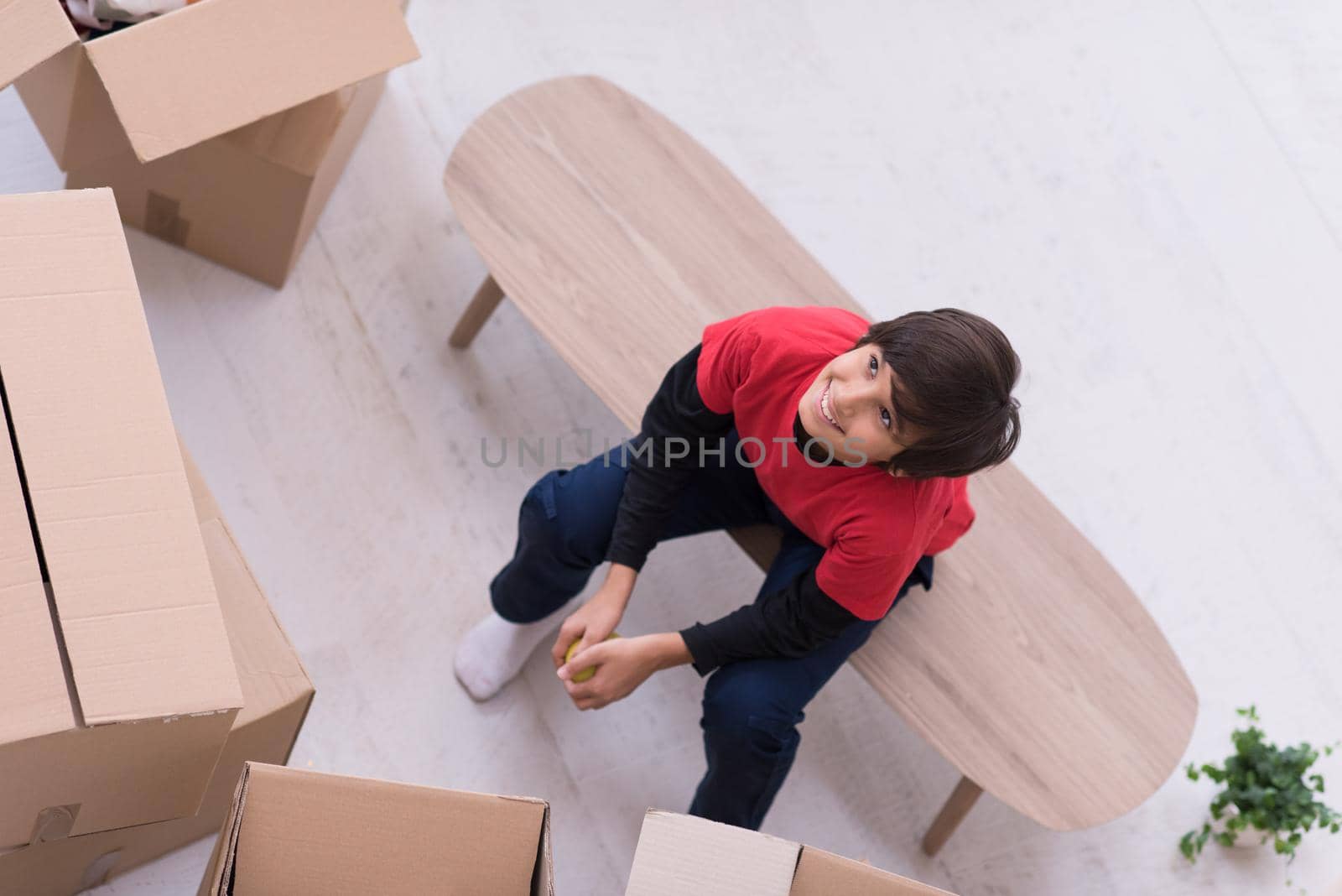 boy sitting on the table with cardboard boxes around him top view by dotshock
