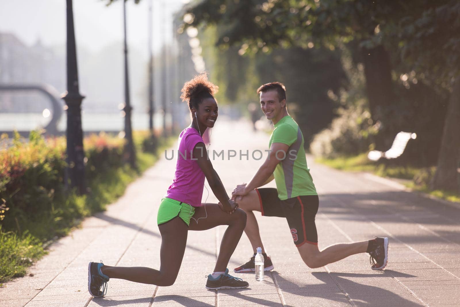 Young multiethnic jogging couple warming up and stretching before morning running in the city