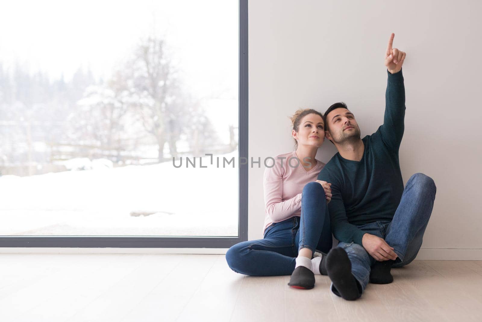 happy young couple sitting near window at home on cold winter day