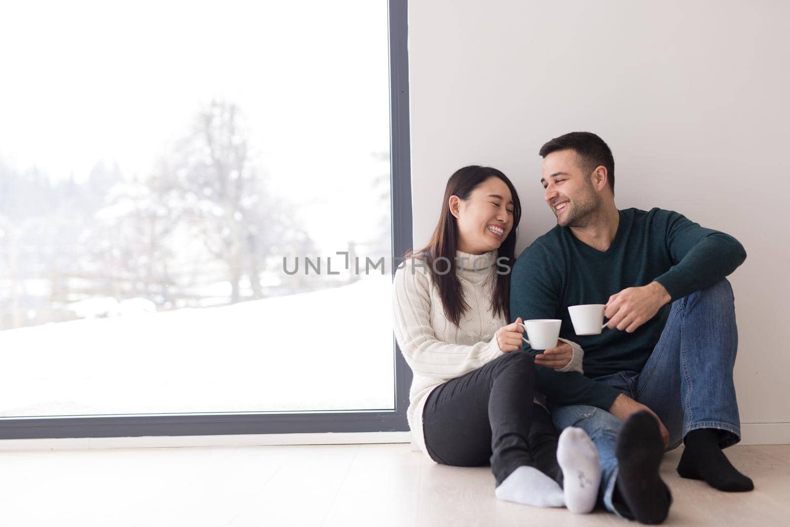 multiethnic couple enjoying morning coffee by the window by dotshock