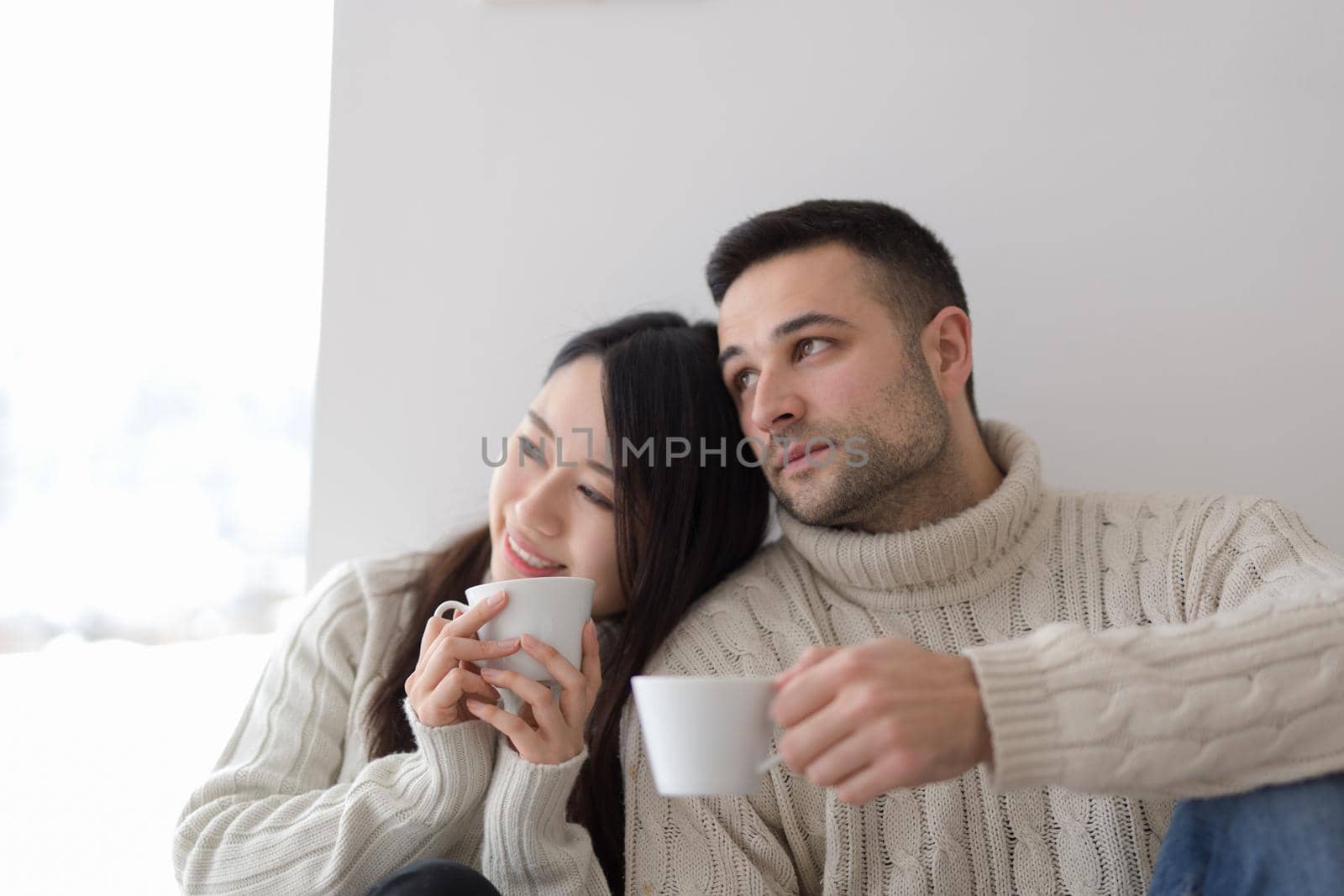 multiethnic couple enjoying morning coffee by the window by dotshock