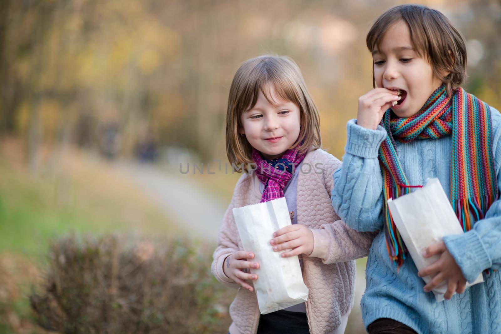 happy kids in park eating popcorn while having fun on beautyful autumn day