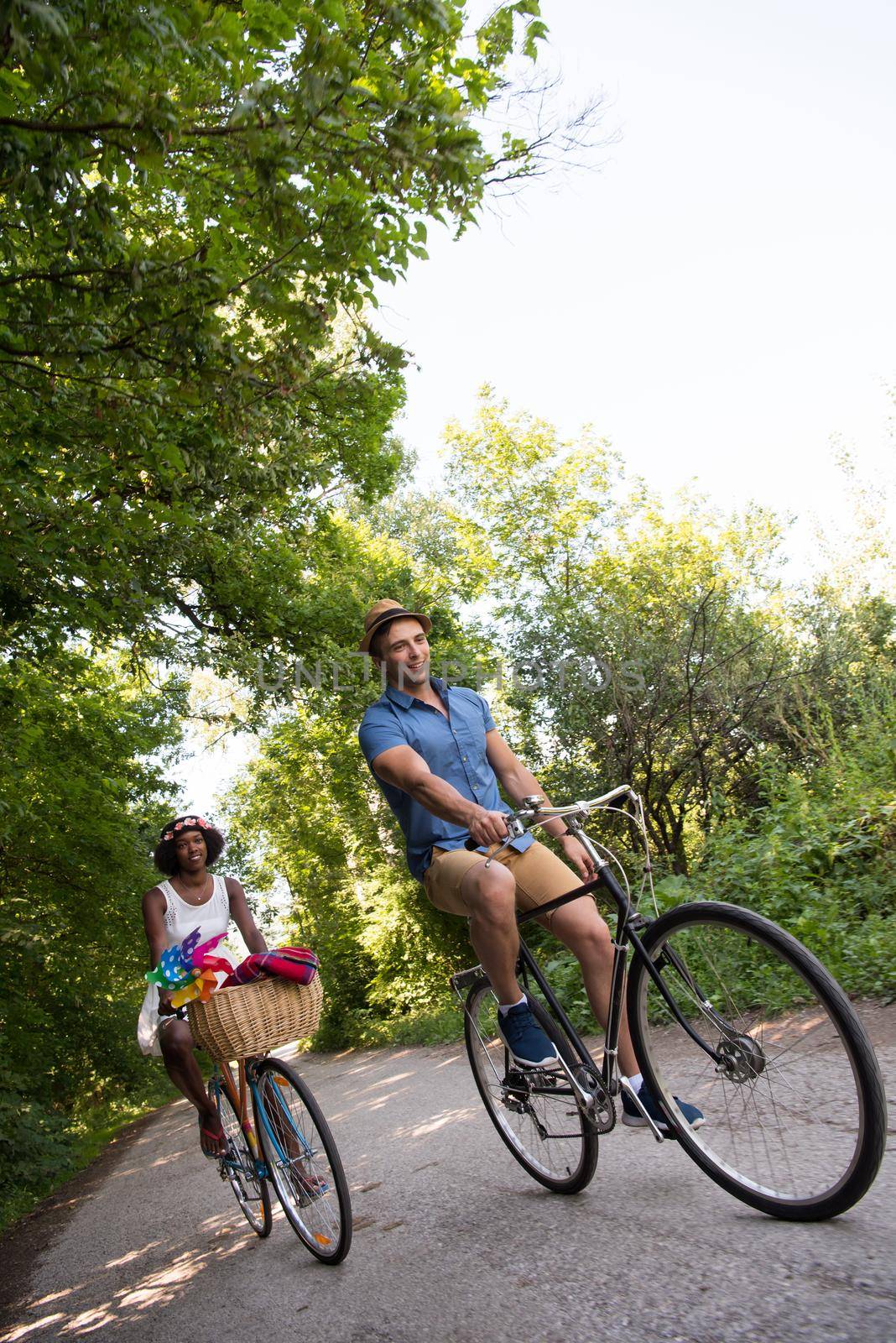 a young man and a beautiful African American girl enjoying a bike ride in nature on a sunny summer day