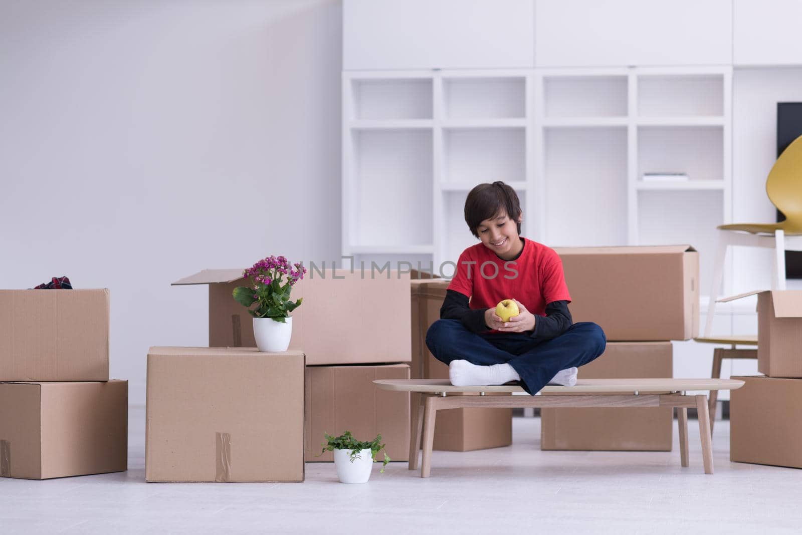 boy sitting on the table with cardboard boxes around him by dotshock