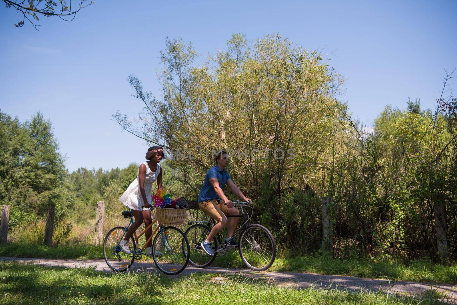 a young man and a beautiful African American girl enjoying a bike ride in nature on a sunny summer day