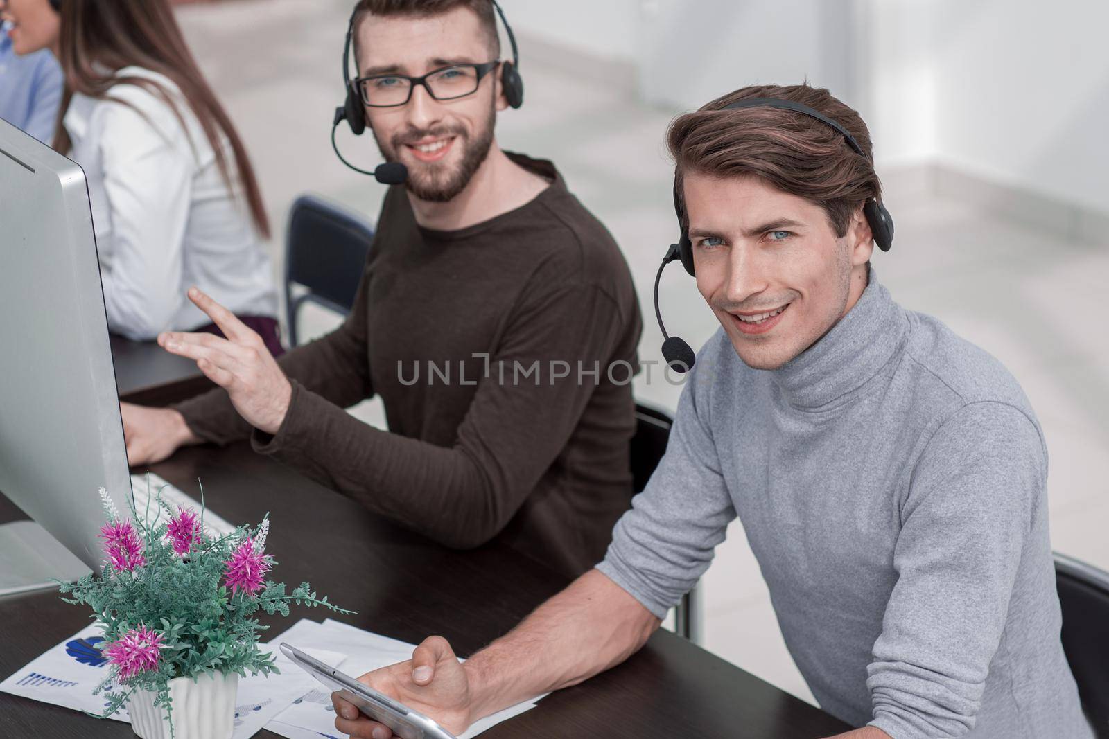 employees of the business center with a headset in the workplace by asdf
