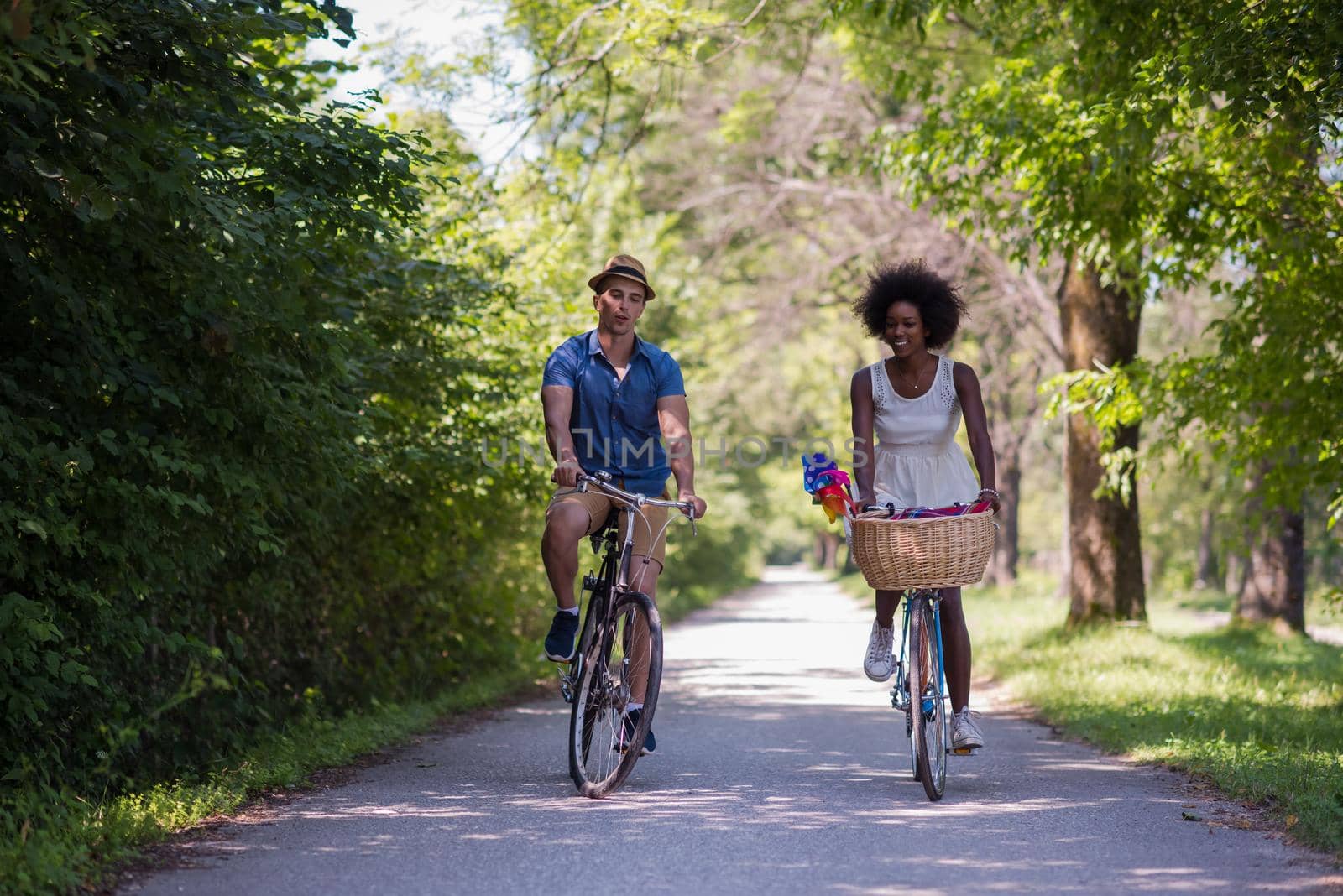 a young man and a beautiful African American girl enjoying a bike ride in nature on a sunny summer day