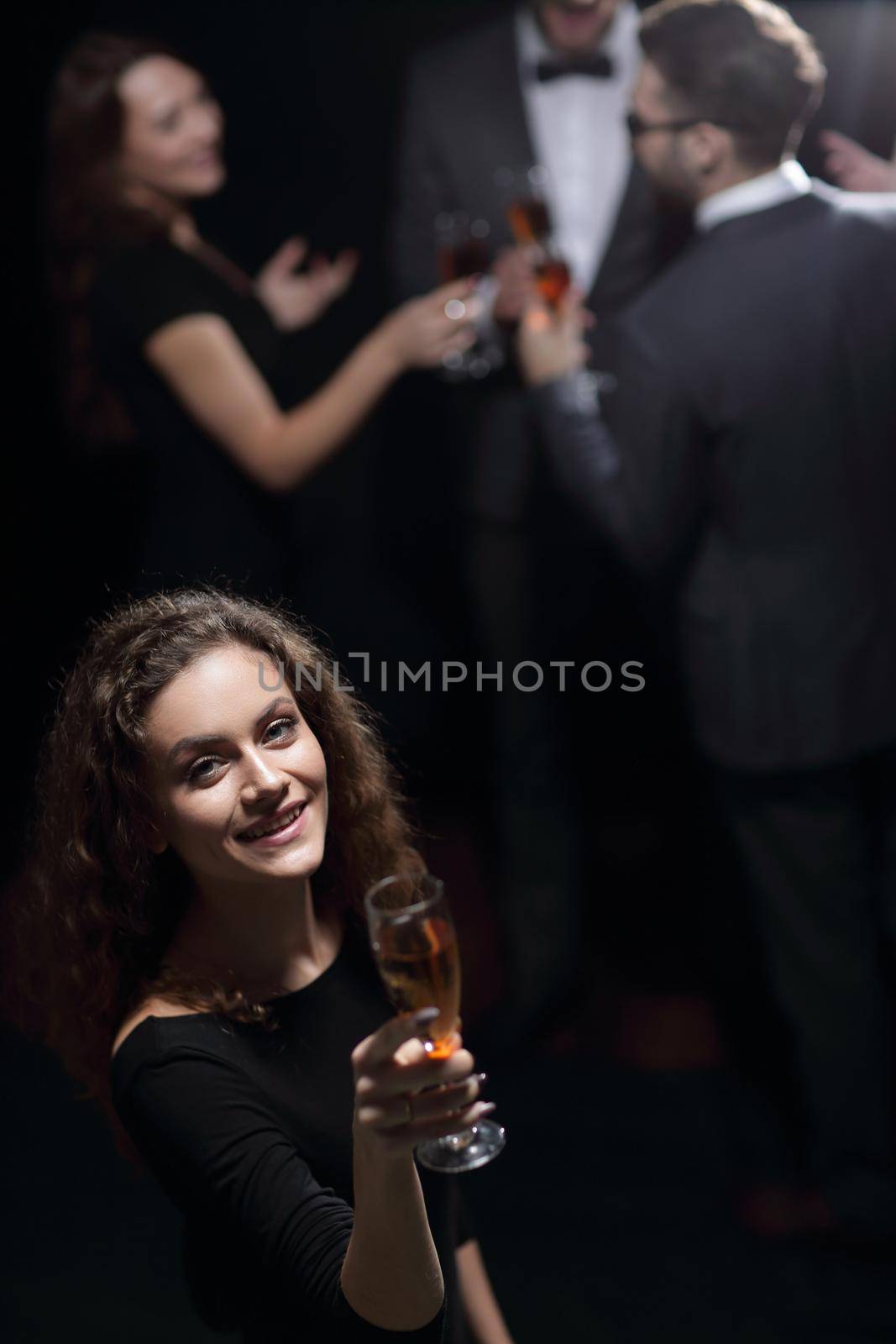 stylish young woman with glass of champagne on the background of friends