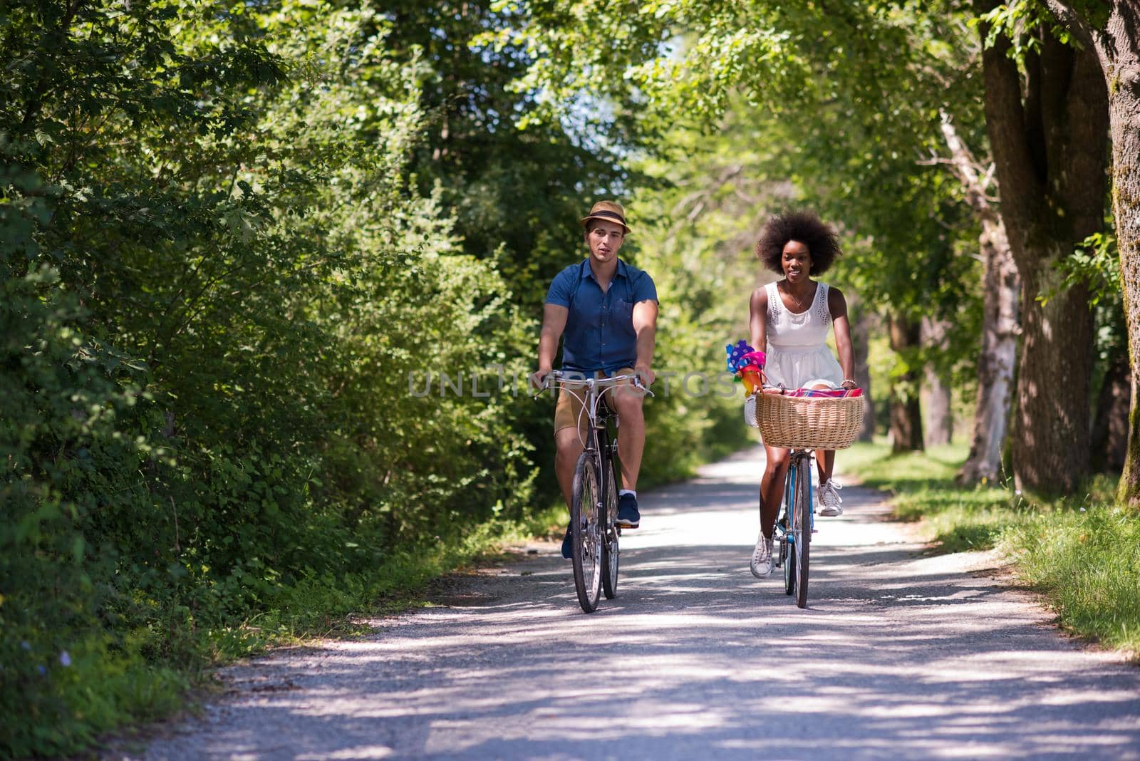 a young man and a beautiful African American girl enjoying a bike ride in nature on a sunny summer day