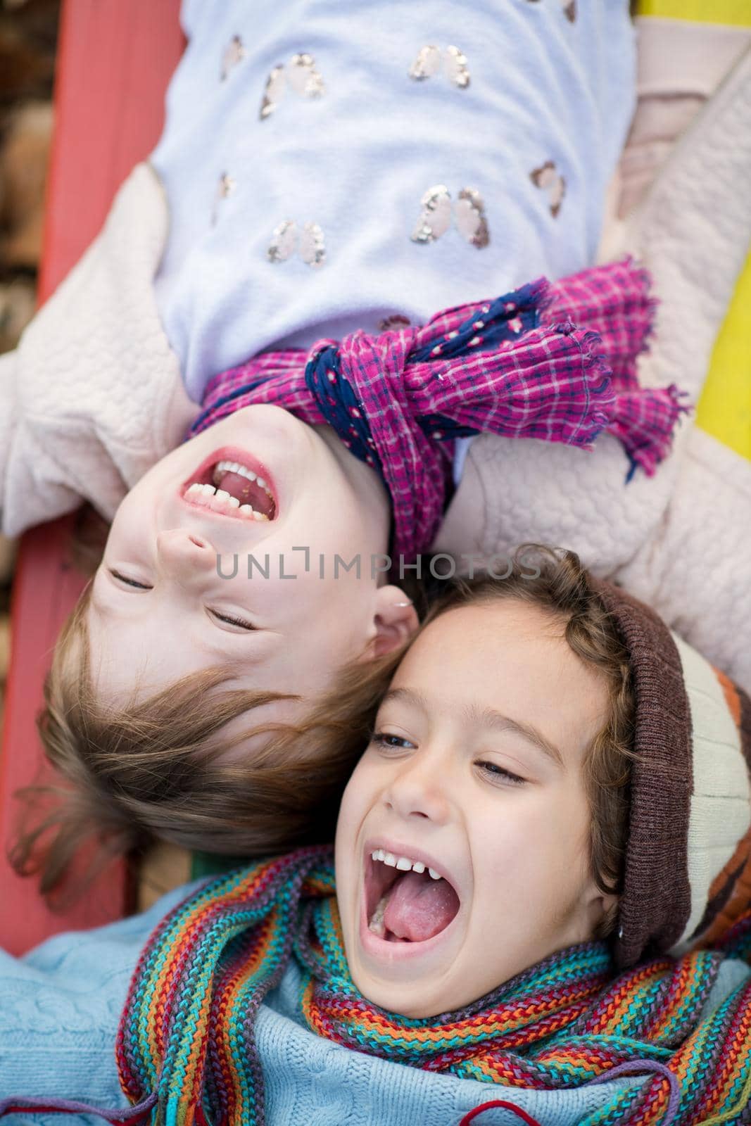 cutte little girl and boy in childrens park having fun and joy while playing in playground on autumn cloudy day