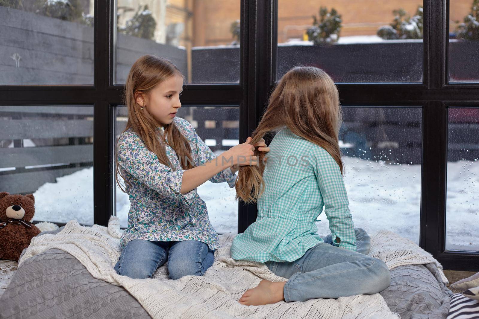 The image of two cute little sisters sitting on windowsill in peace and quiet by nazarovsergey