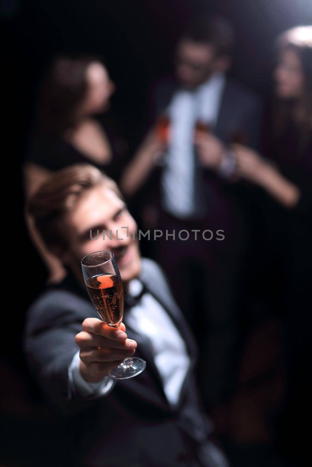 stylish young man standing with a glass of champagne. by asdf