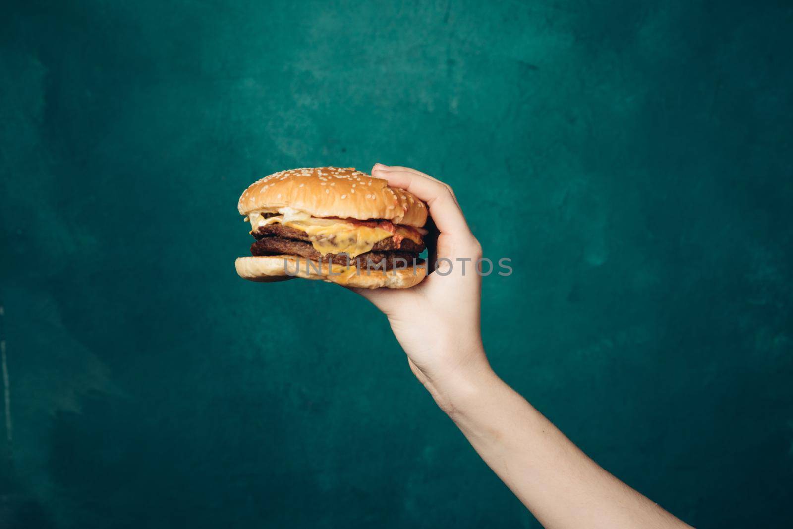 hamburger in hands close-up fast food green background by Vichizh