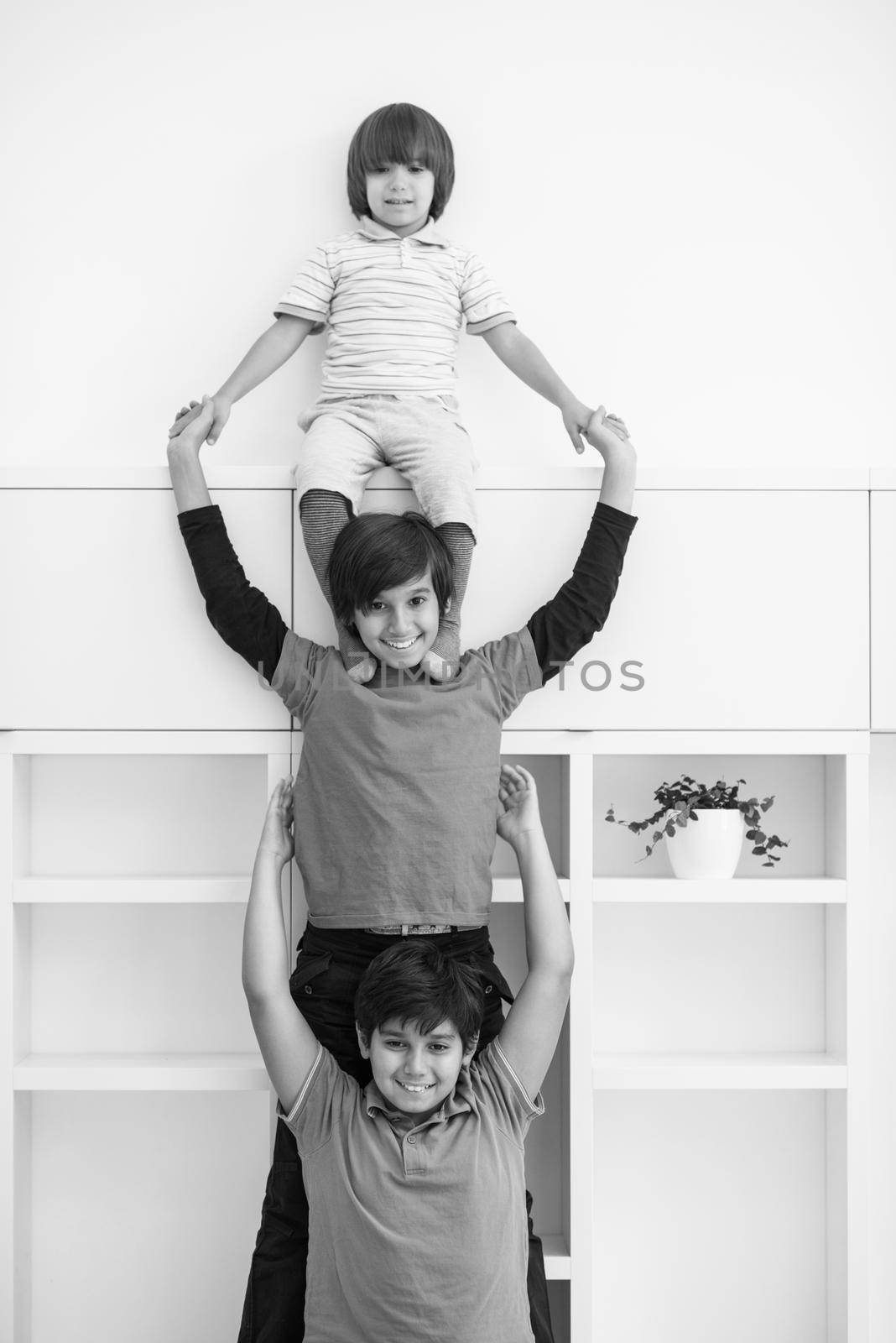happy young boys having fun and posing line up piggyback in new modern home